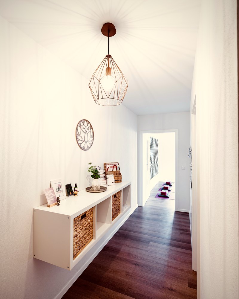 Heller Flur mit Kupferlampe und Blick in den Yogaraum