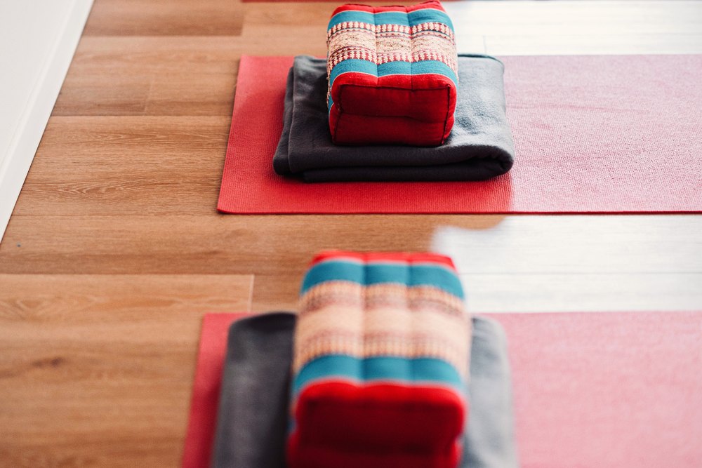 Rote Yogamatten mit Kissen und Decken auf dem Holzboden